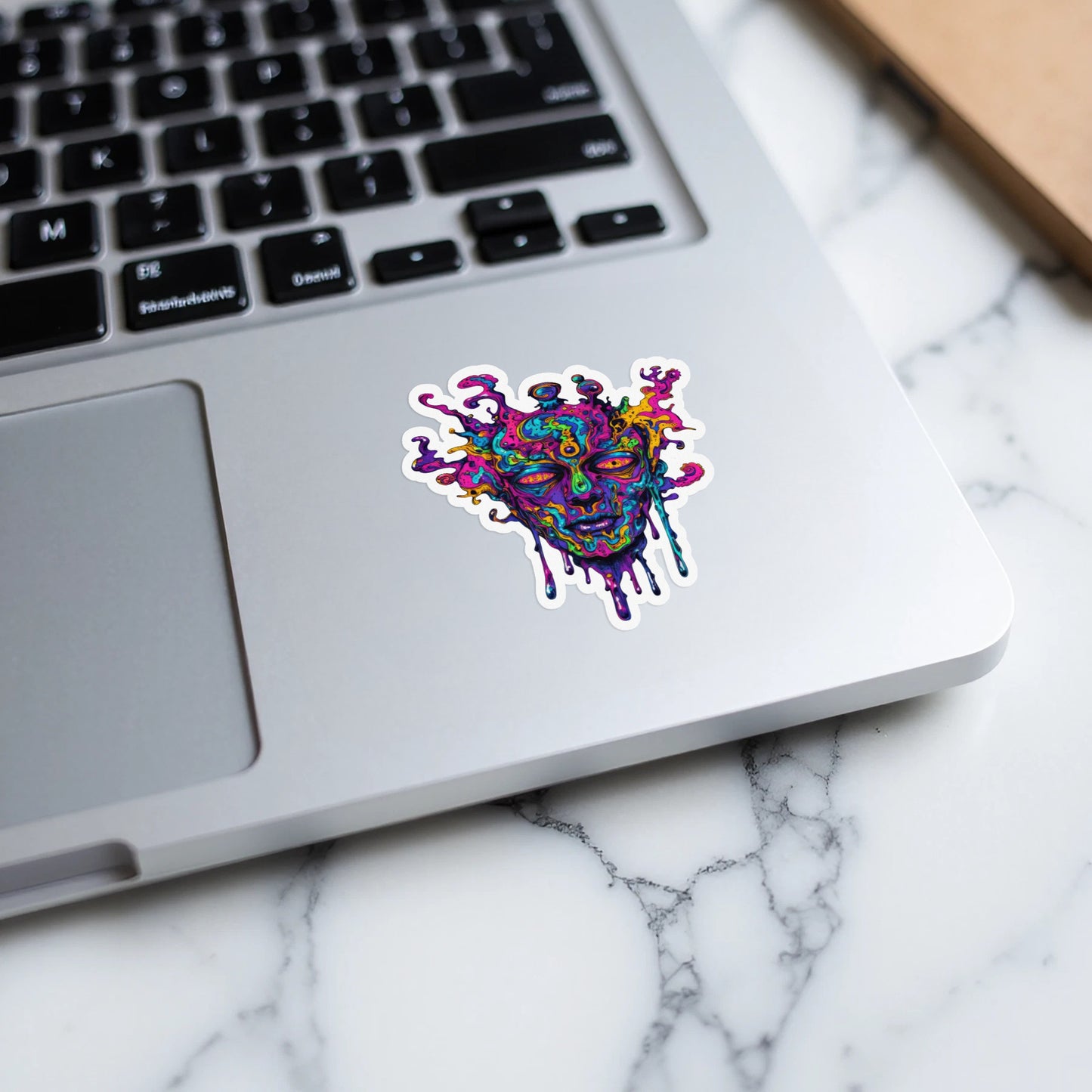 Colorful, melting psychedelic face sticker on a laptop keyboard.
