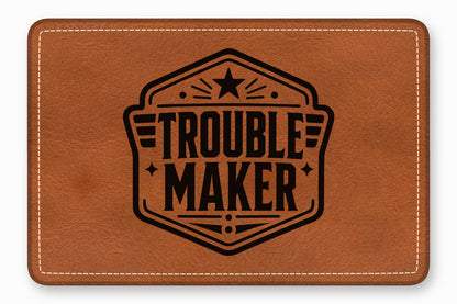 Brown leather patch with white stitched border, featuring a black printed emblem that reads TROUBLE MAKER.