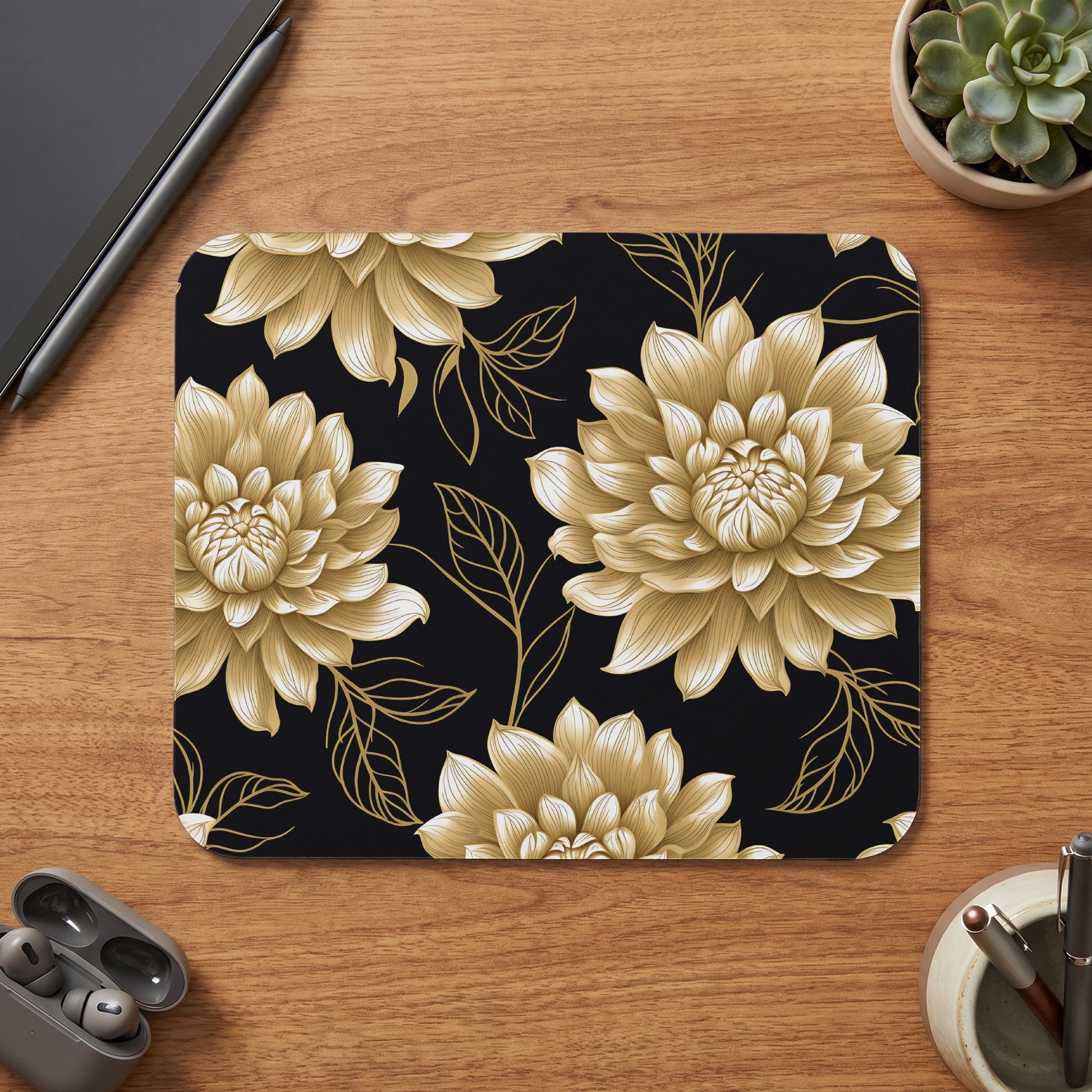 Mousepad with gold floral pattern on black background on a wooden desk.
