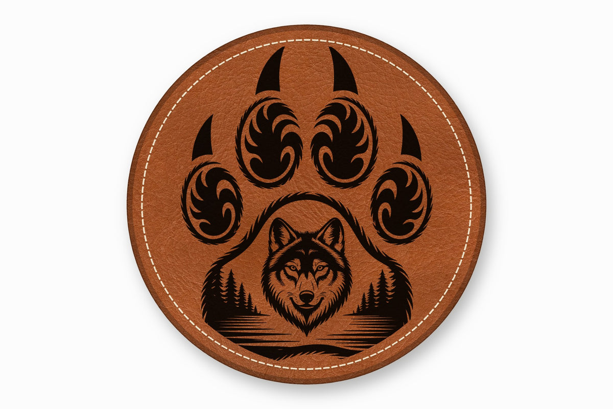 Round brown leather patch with white stitching featuring a black wolf head and forest inside a paw print.