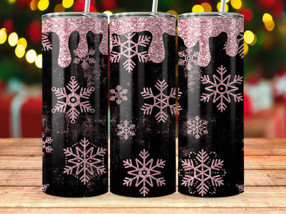 Three black tumblers with pink glitter drips and snowflakes against a blurred holiday background.