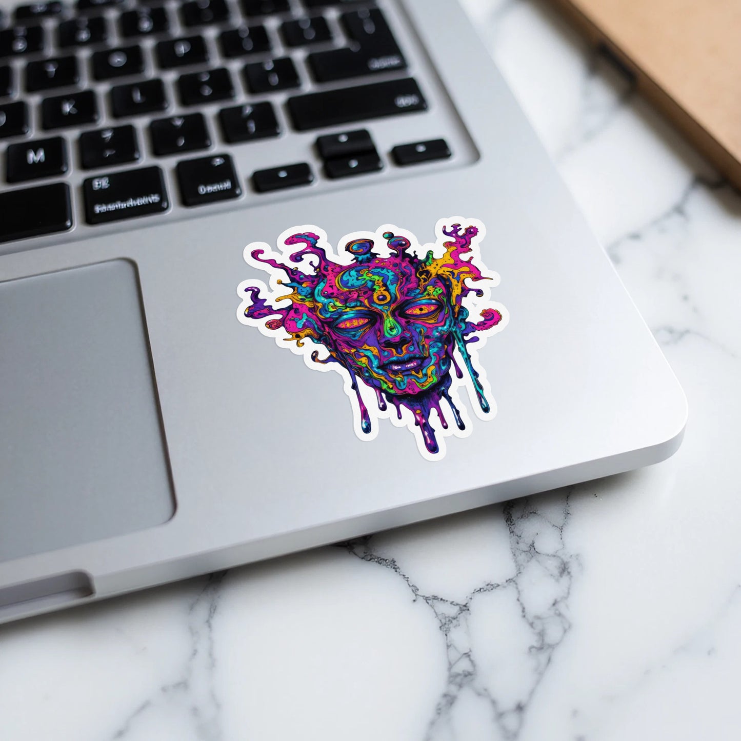 Psychedelic melting face sticker on a laptop keyboard.