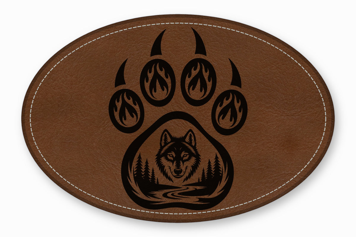 Brown oval leather patch featuring a black bear paw print with a wolf and forest scene inside.