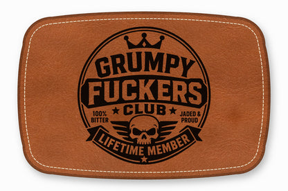 Brown leather patch with rounded corners, white stitching, and a black skull and text graphic.