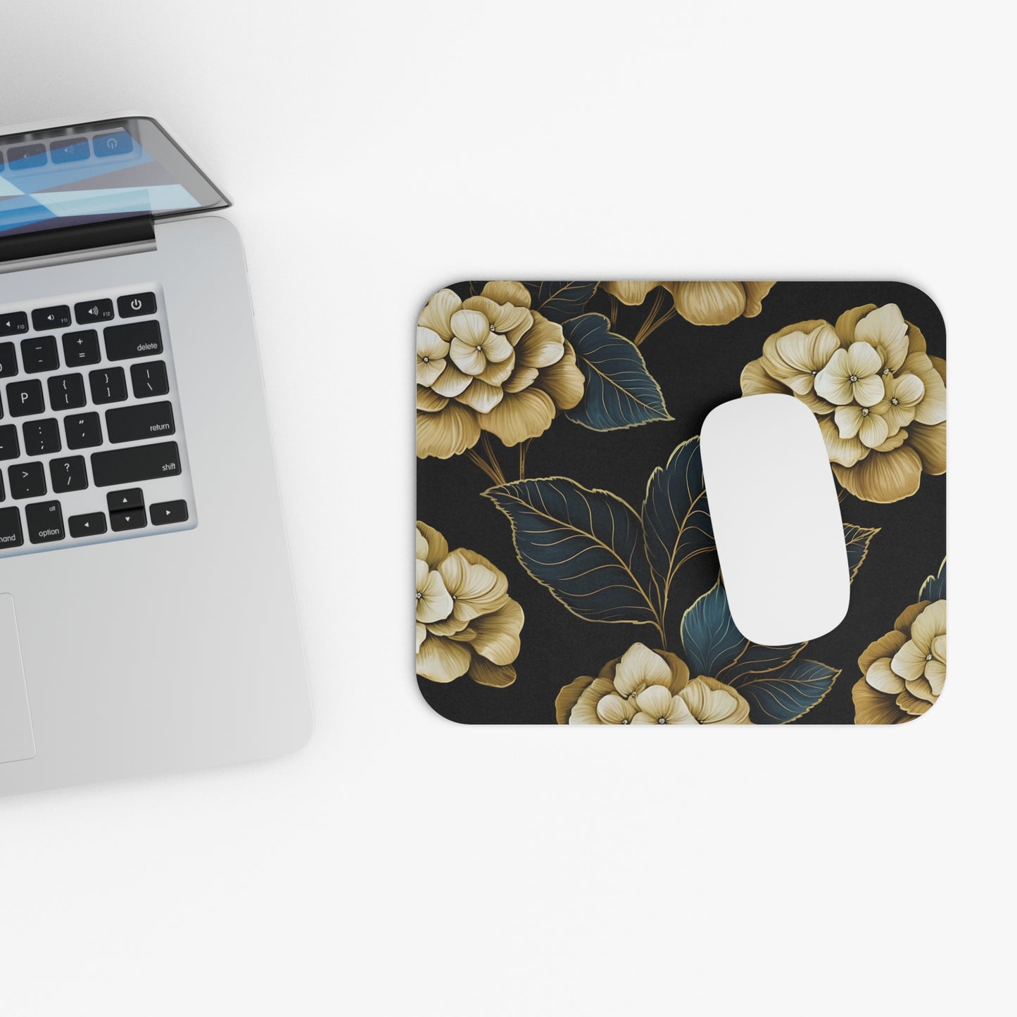 Mousepad with gold hydrangea floral pattern and white mouse near laptop.