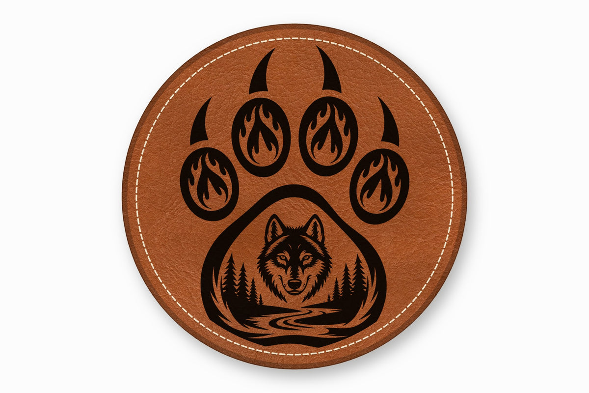 Round brown leather coaster with white stitched border and a black bear paw and wolf design.