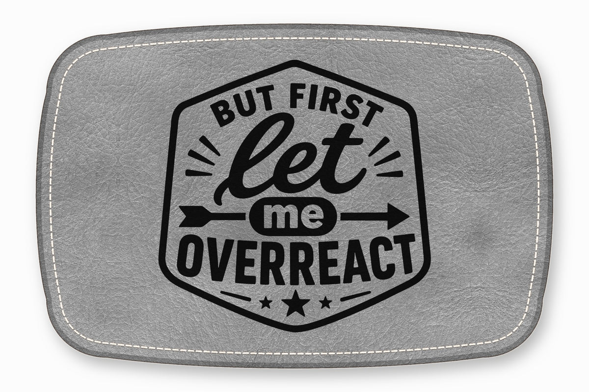 Gray faux leather patch with white stitched borders and a black emblem reading But first let me overreact.