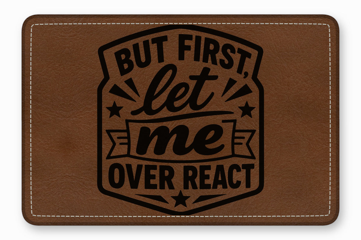 A brown leather patch with white stitched borders and black engraved text reading, "But first, let me overreact."