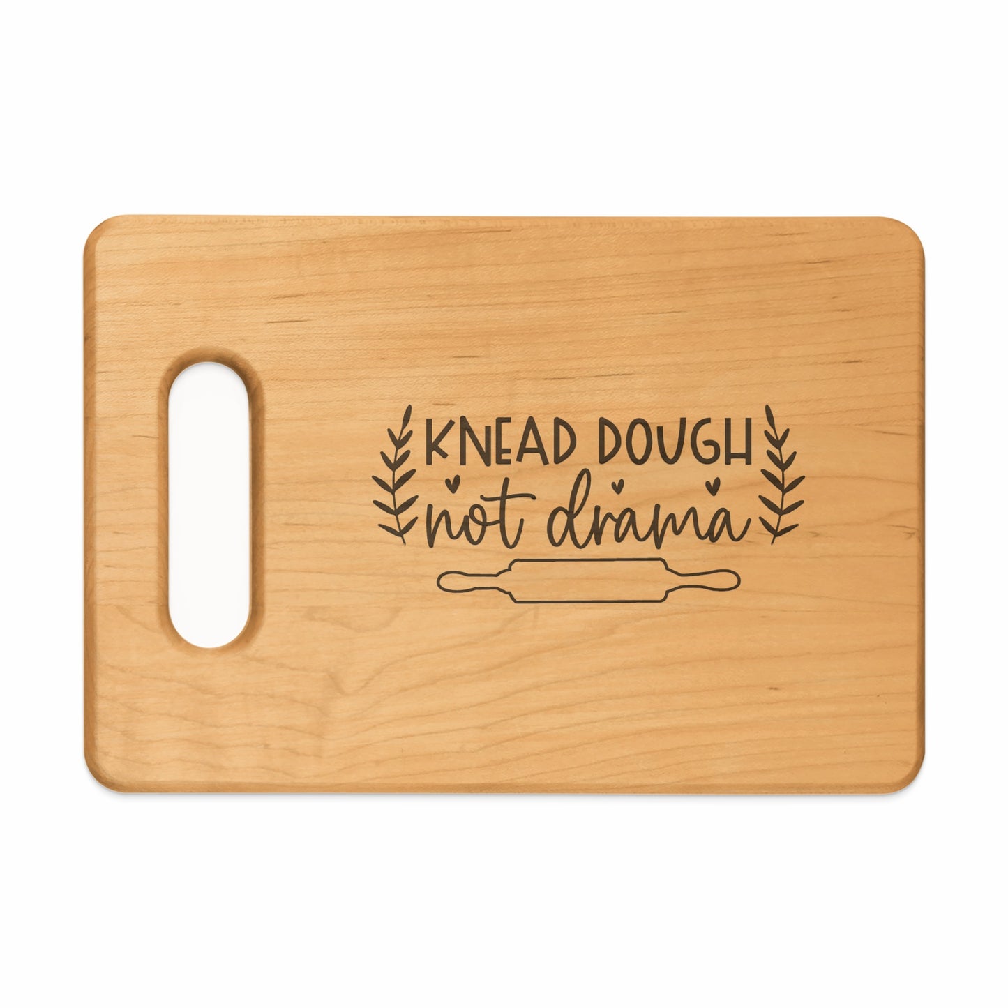 Wooden cutting board with engraved text "knead dough not drama" and rolling pin design.
