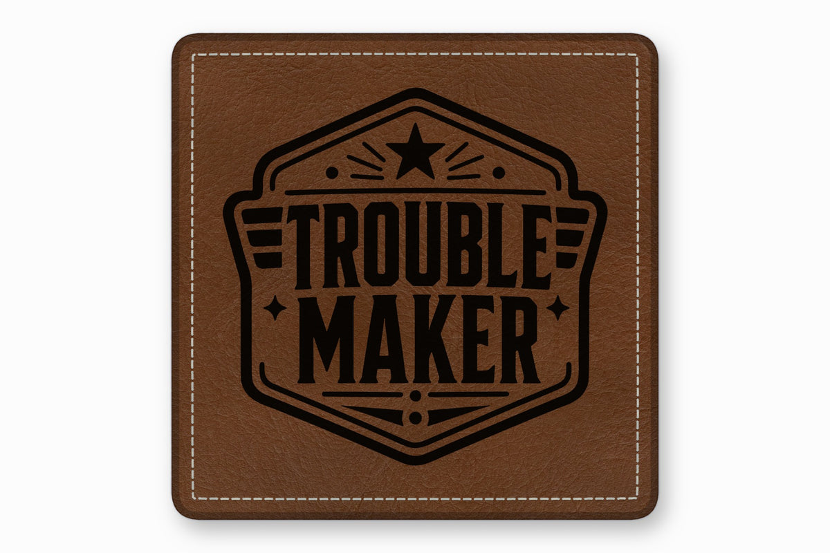 Square brown leather patch with white stitched border and black stamped "Troublemaker" text emblem.