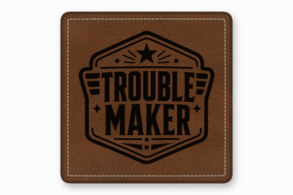 Square brown leather patch with white stitched border and black stamped "Troublemaker" text emblem.
