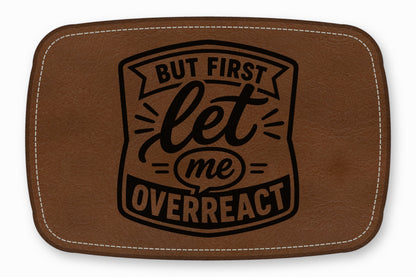 Brown faux leather patch with white stitched border and black text that reads But First Let Me Overreact.