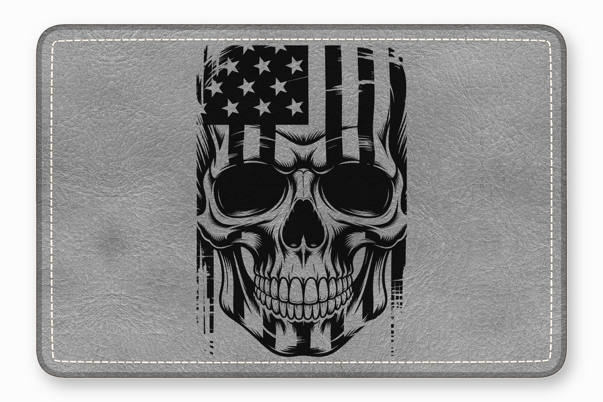 A rectangular grey leather mousepad featuring a black and white graphic of a skull with an American flag design.