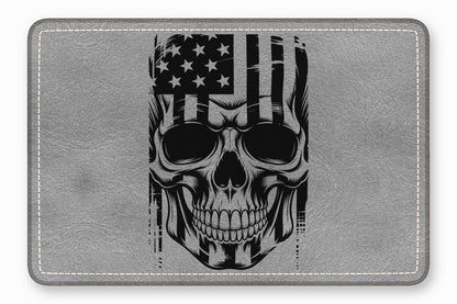 A rectangular grey leather mousepad featuring a black and white graphic of a skull with an American flag design.
