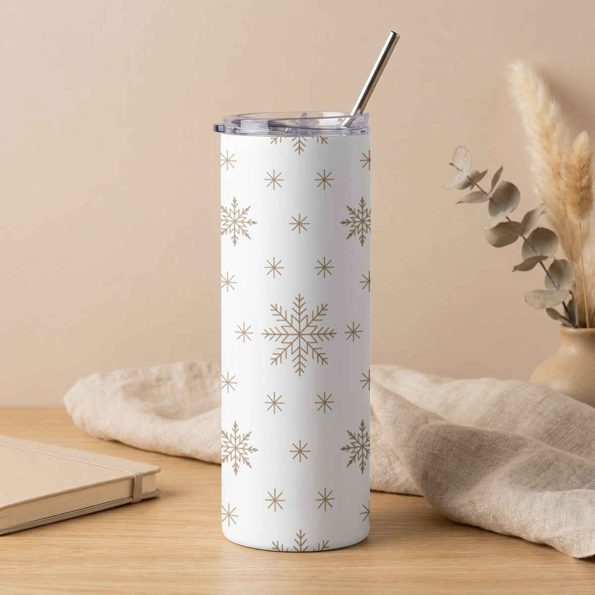 White tumbler with gold snowflake pattern and metal straw.