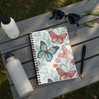 Spiral bound notebook with butterfly and floral pattern on a wooden table.