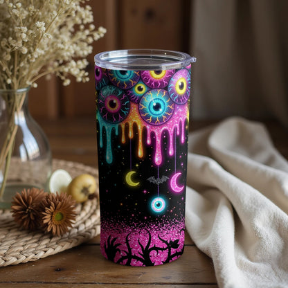Tumbler with dripping eyeballs, moons, bat, and spooky trees on a black background.