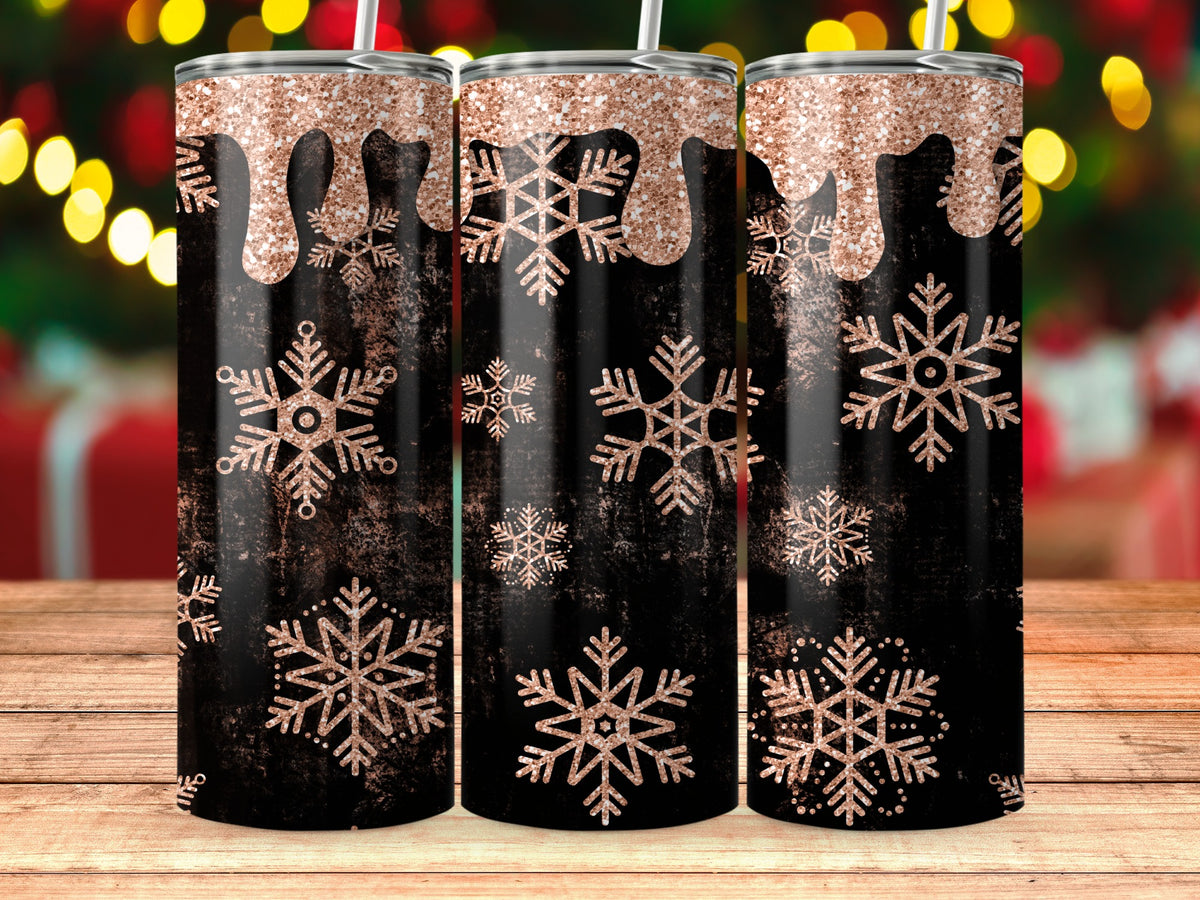 Black tumbler with rose gold glitter drips and snowflakes on wooden surface.