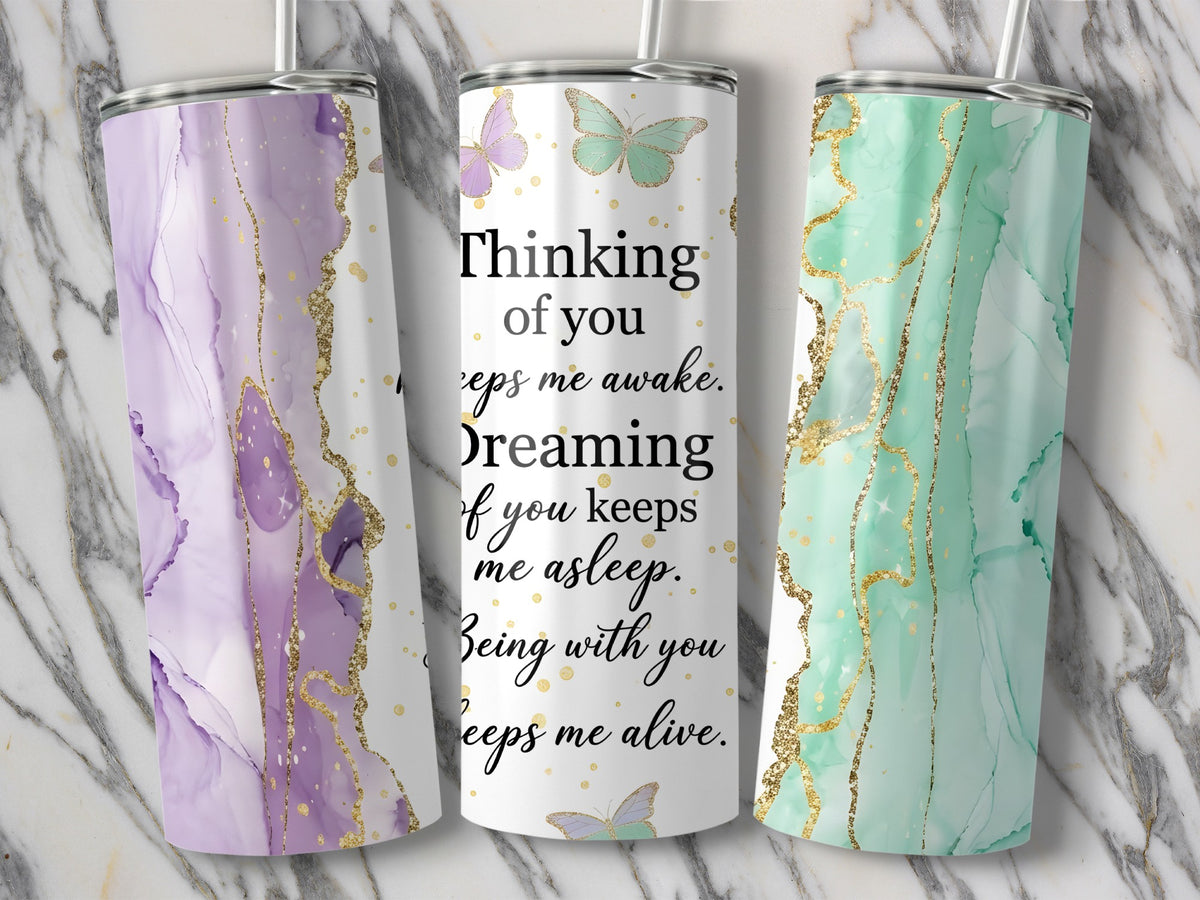 Three tumblers with marble and gold designs, one with text about thinking of you.