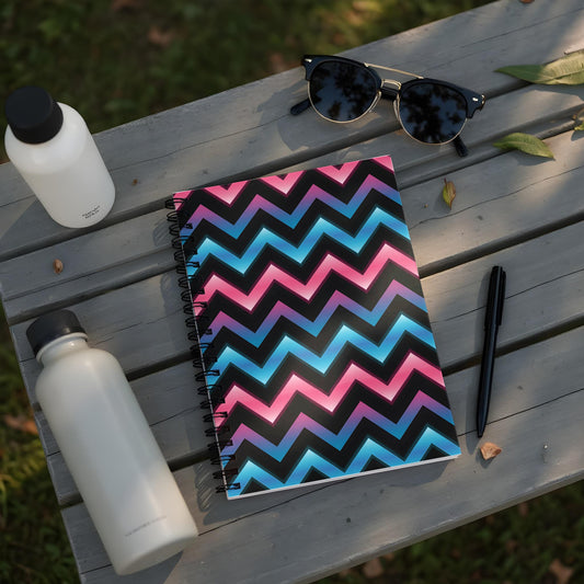 Spiral notebook with pink, blue, and black chevron pattern on a wooden bench.