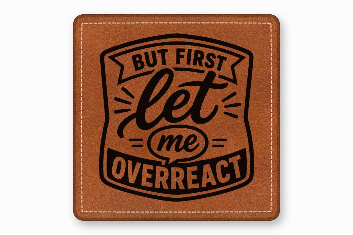 A square brown leather patch with white stitched borders and black text that reads, "BUT FIRST let me OVERREACT".