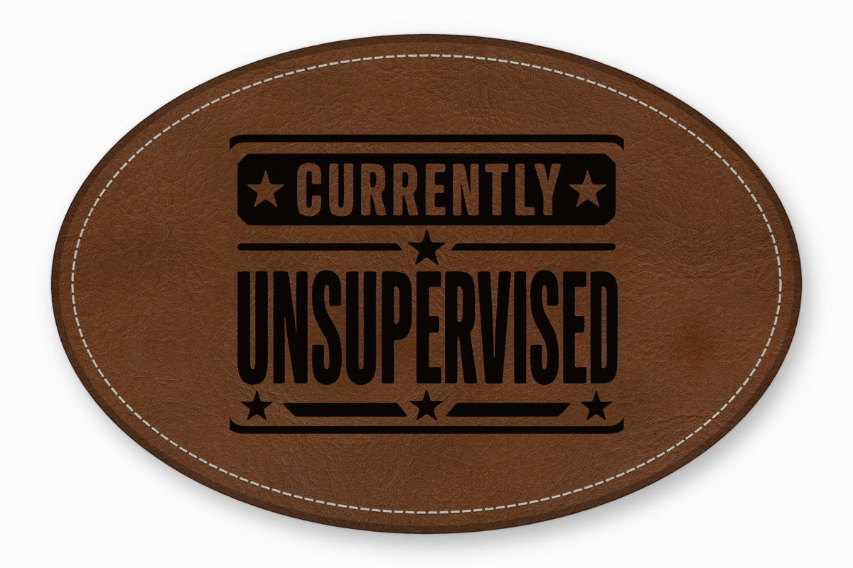 An oval brown leather patch with white stitched borders and black debossed text reading CURRENTLY UNSUPERVISED.