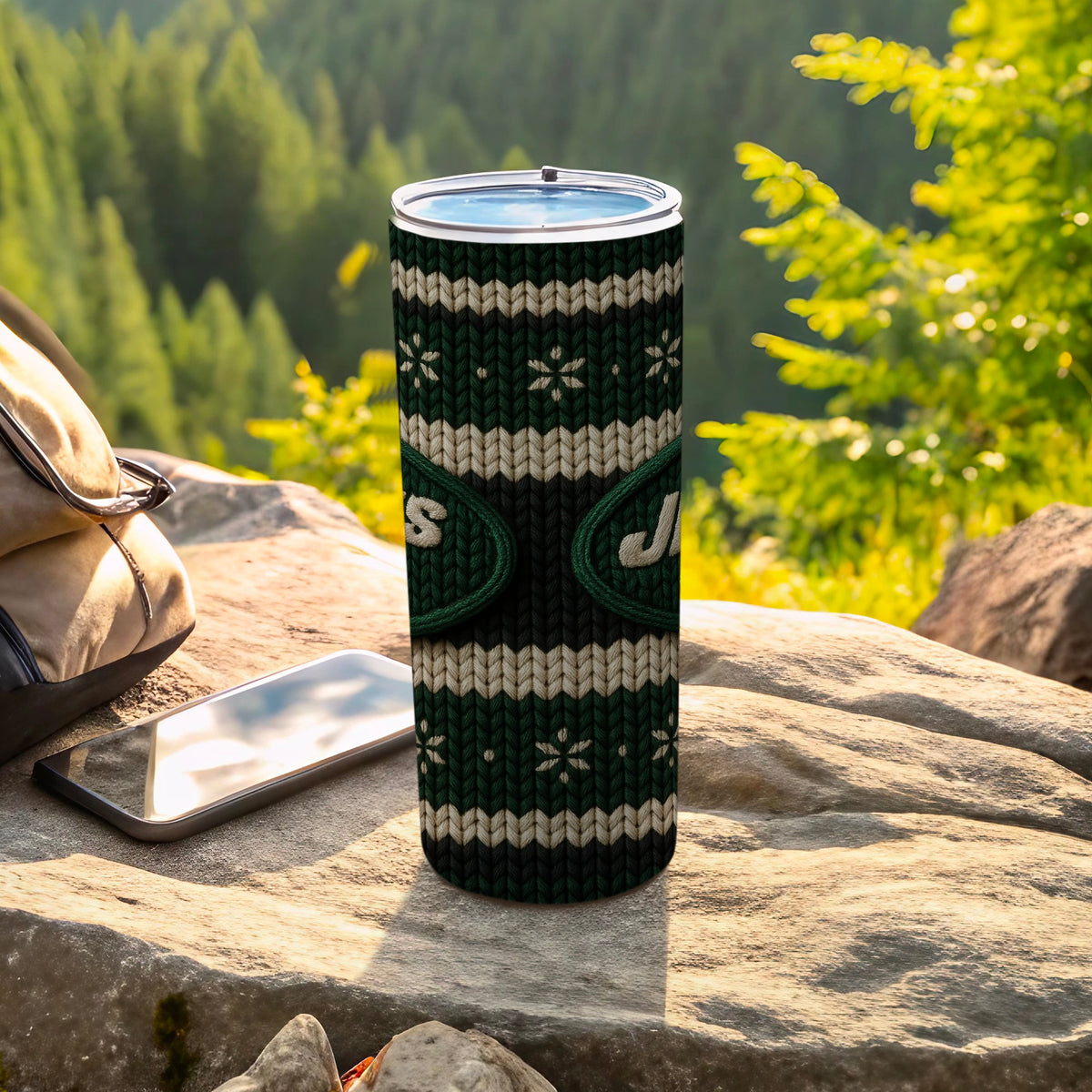 Green and white knit tumbler with "Jets" logo outdoors on rock.