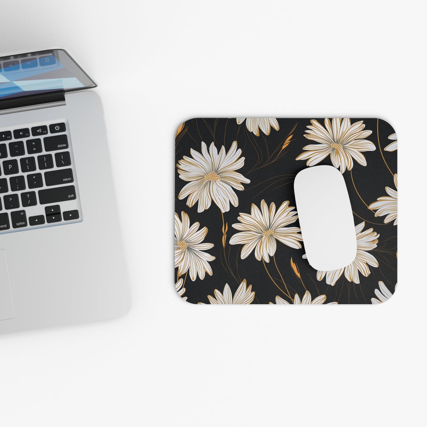 Mousepad with white and gold floral pattern next to laptop and white mouse.