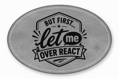 An oval gray faux leather patch featuring the black text But First Let Me Over React.