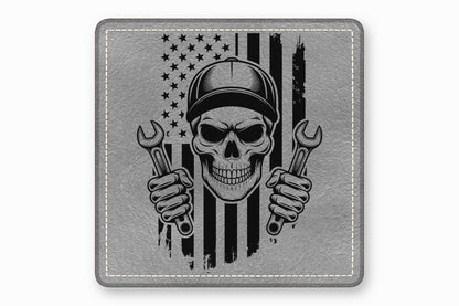 Square gray leatherette patch with stitched border, featuring a skull mechanic wearing a cap and holding wrenches against a distressed American flag.