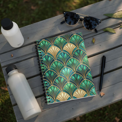 Notebook with art deco green and gold fan pattern, on a wooden bench with water bottles and sunglasses.