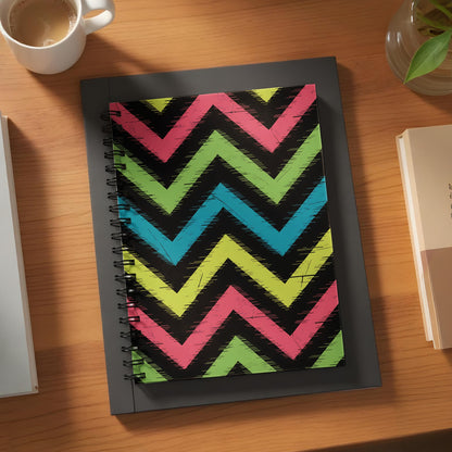 Notebook with a black cover featuring a pink, green, and teal chevron pattern.