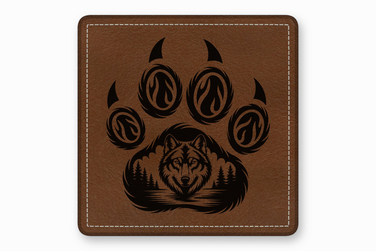 Brown square leather patch engraved with a bear paw containing a wolf face and forest landscape.