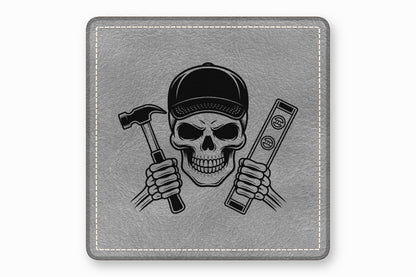 Square grey leather patch featuring a black illustration of a skull in a baseball cap holding a hammer and a level.