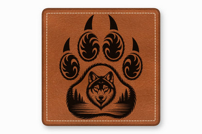 Square brown leather patch with white stitching featuring a black paw print enclosing a wolf head and forest landscape.