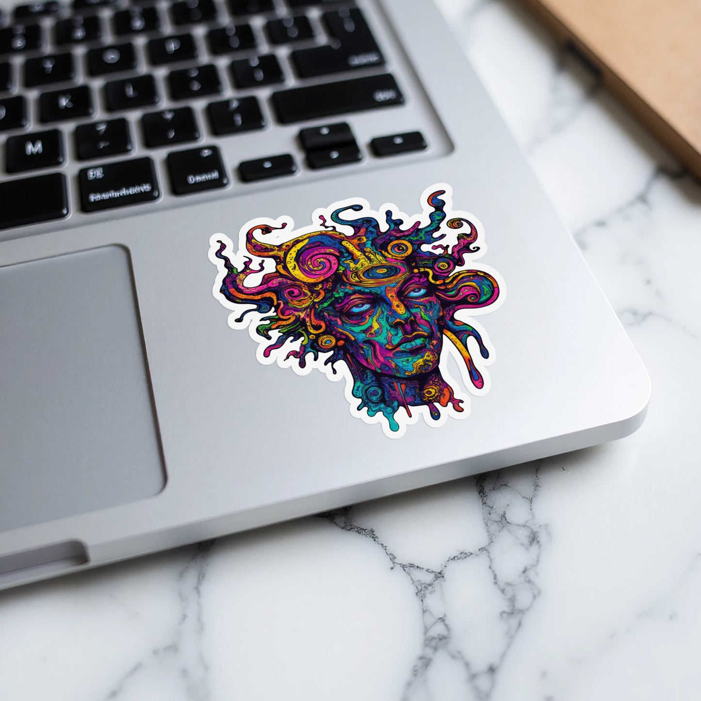Colorful abstract sticker of a face with snake-like hair on a laptop.