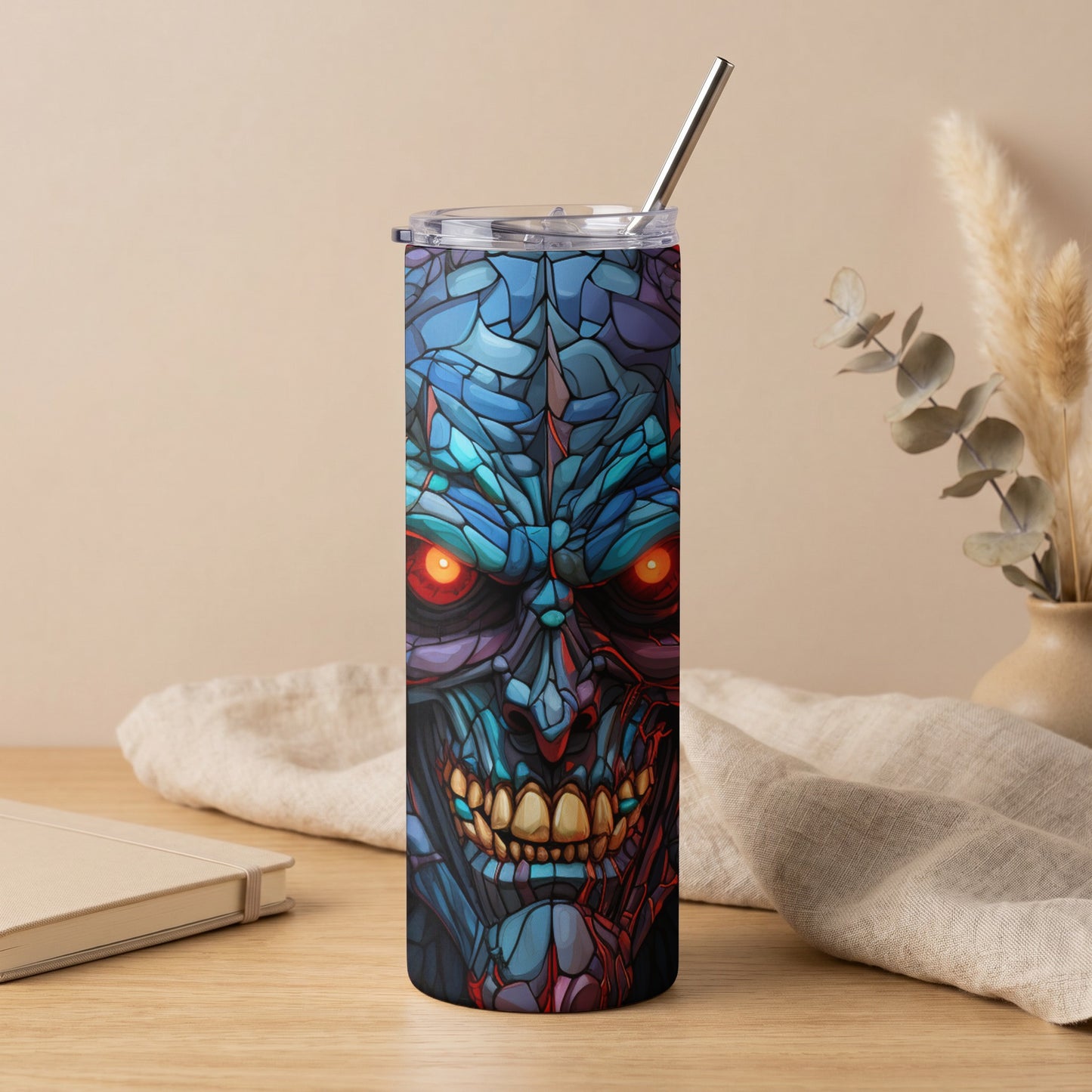 Tumbler with mosaic-style monster face and red glowing eyes, featuring a metal straw.