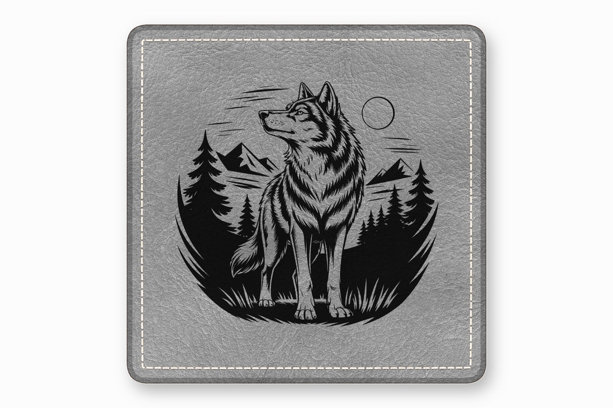 Gray square leather patch featuring a black engraved illustration of a wolf standing before mountains and pine trees.