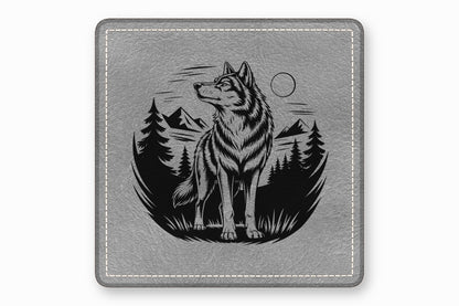 Gray square leather patch featuring a black engraved illustration of a wolf standing before mountains and pine trees.