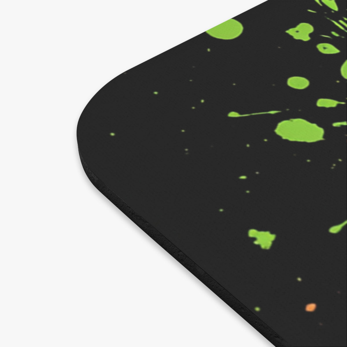 Black mousepad with green and orange paint splatters.