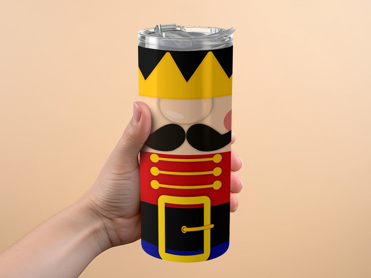 Tumbler with nutcracker design, held in a hand against a peach background.