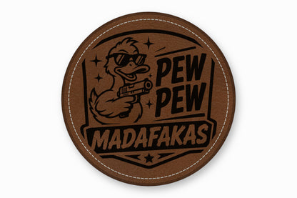 A round brown leather patch features a duck in sunglasses holding a gun, with text reading "PEW PEW MADAFAKAS".