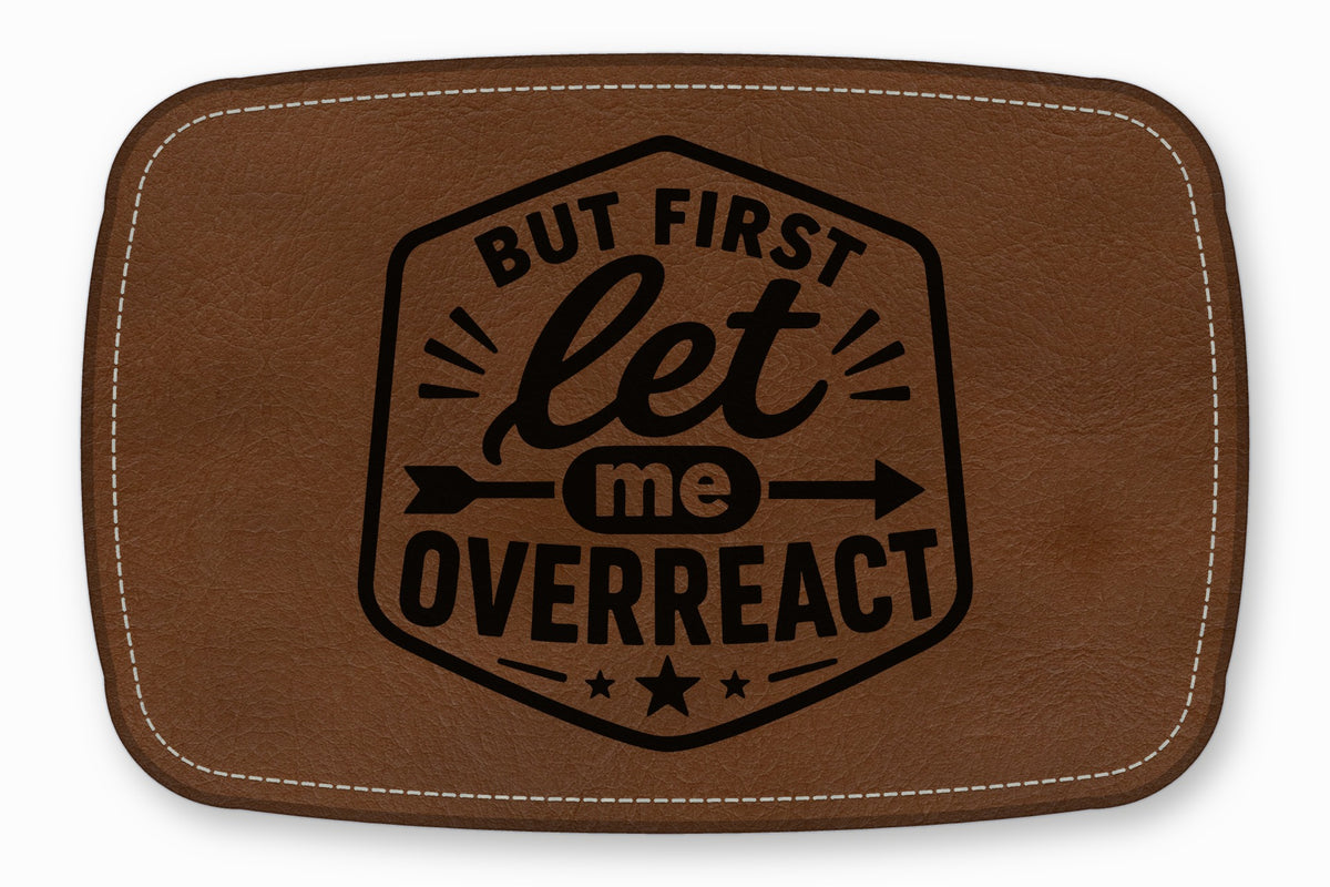 Brown leather patch with white stitched border, featuring the black text But First Let Me Overreact.