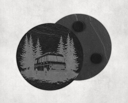 Circular slate coaster with etched forest scene and RV, second coaster behind.