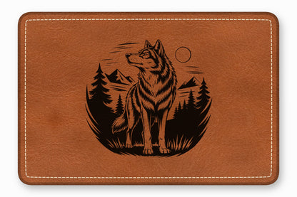 Brown leather patch with rounded corners, white stitching, and a black engraved wolf landscape design.