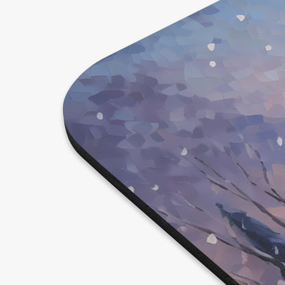 Mousepad with a painting of a dark bird on a branch with falling snow.