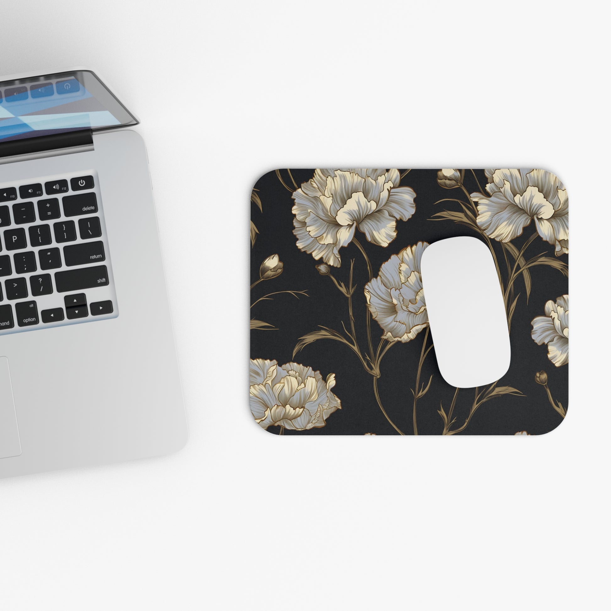 Floral mousepad with white mouse next to a laptop.