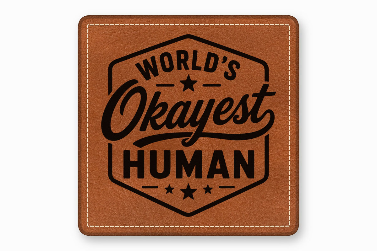 Brown square leather patch with stitched borders and the text Worlds Okayest Human inside a hexagon.