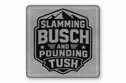 A gray leather patch with white stitched borders and a black mountain emblem containing the text Slamming Busch and Pounding Tush.