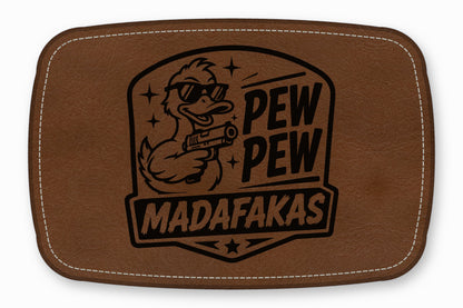 Brown rectangular leather patch with white stitched border and engraved design of a sunglasses-wearing duck holding a gun.
